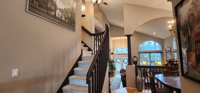 staircase with decorative columns, wood finished floors, high vaulted ceiling, and arched walkways