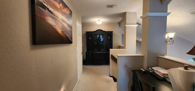 hall featuring a textured ceiling, visible vents, a textured wall, and light colored carpet