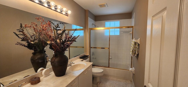 full bathroom featuring a sink, double vanity, combined bath / shower with glass door, visible vents, and toilet