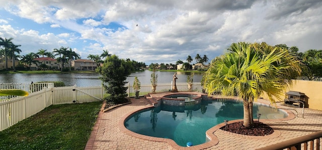 view of pool featuring a pool with connected hot tub, a patio area, a water view, a fenced backyard, and a gate