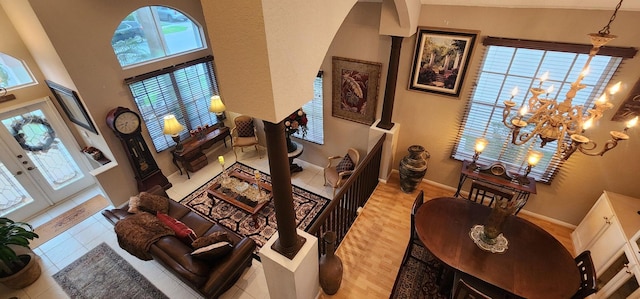 interior space with arched walkways, an inviting chandelier, wood finished floors, baseboards, and a towering ceiling
