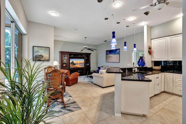 kitchen with sink, hanging light fixtures, white cabinets, decorative backsplash, and kitchen peninsula