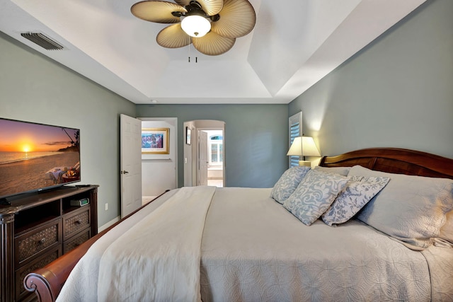 bedroom with ceiling fan, connected bathroom, and a tray ceiling