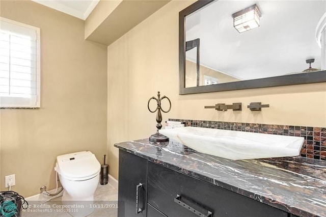 half bath with baseboards, vanity, toilet, and tile patterned floors