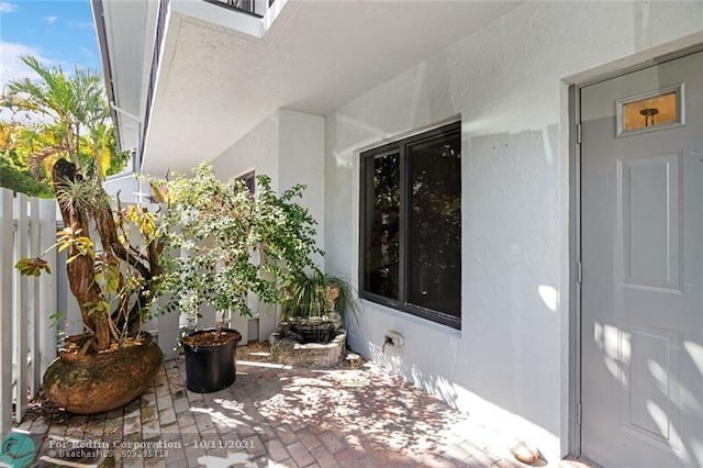 property entrance featuring a patio area, fence, and stucco siding