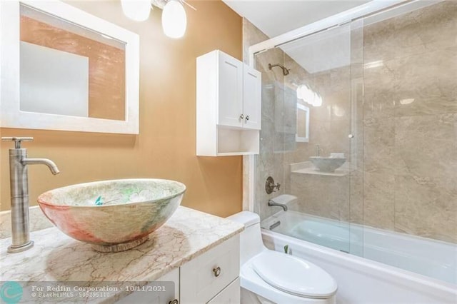 full bathroom with bath / shower combo with glass door, vanity, and toilet