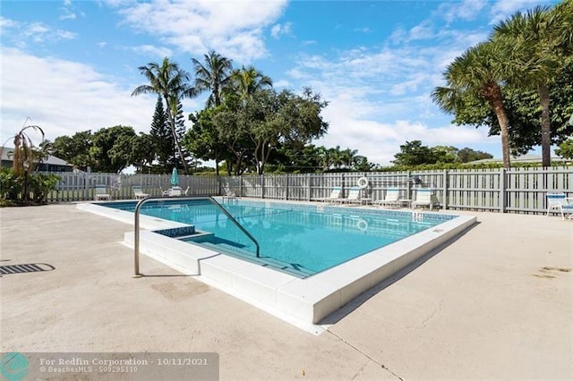 community pool with a patio area and fence