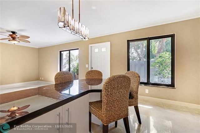 dining room featuring ornamental molding, baseboards, and ceiling fan with notable chandelier