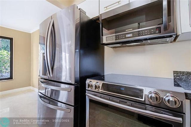 kitchen featuring baseboards, appliances with stainless steel finishes, ornamental molding, and white cabinets