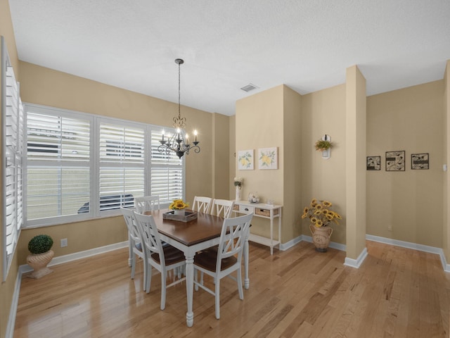 dining space with a chandelier, a textured ceiling, and light hardwood / wood-style floors