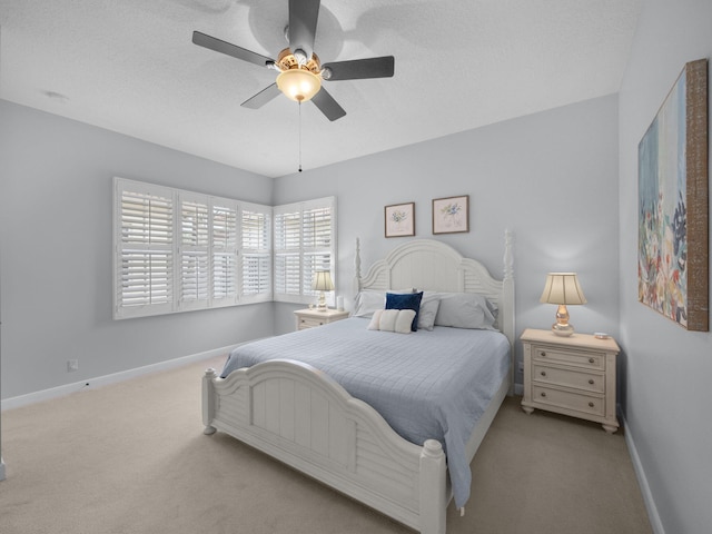 bedroom with ceiling fan, light colored carpet, and a textured ceiling