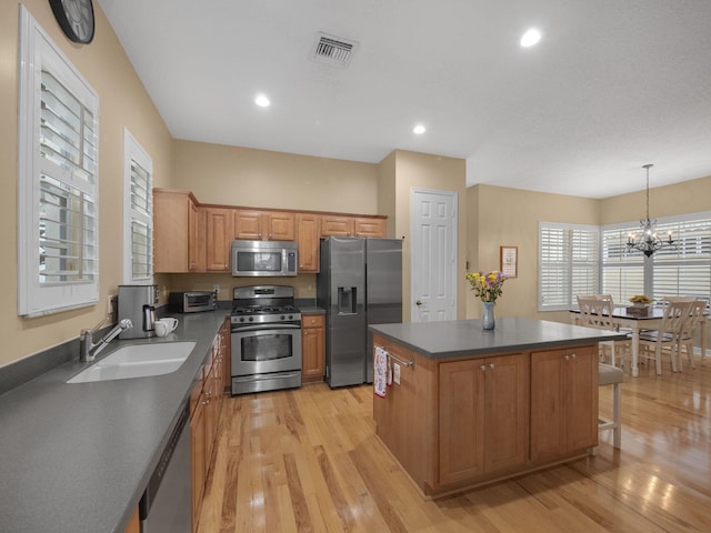 kitchen featuring sink, a kitchen island, pendant lighting, stainless steel appliances, and light hardwood / wood-style floors