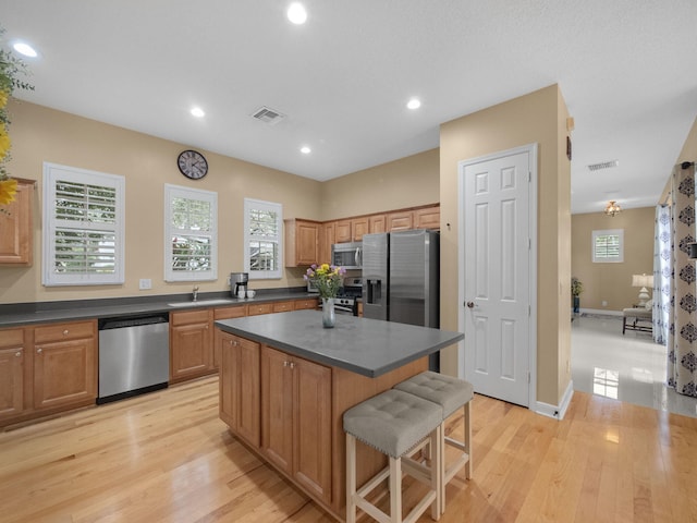 kitchen featuring sink, a breakfast bar, stainless steel appliances, a center island, and light hardwood / wood-style floors