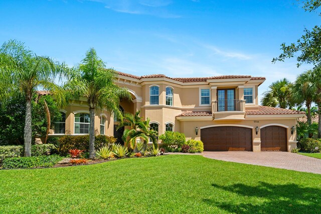 mediterranean / spanish house with a garage, a balcony, french doors, and a front lawn