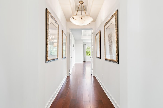 hallway with dark wood-type flooring and a raised ceiling