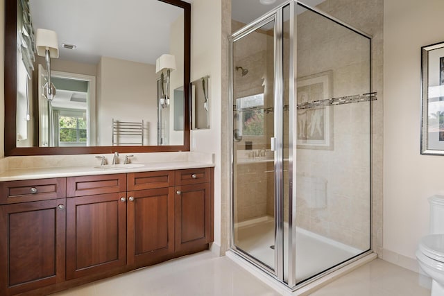 bathroom featuring toilet, vanity, a shower with shower door, and tile patterned floors