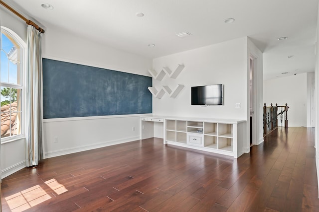 unfurnished living room featuring a healthy amount of sunlight and dark hardwood / wood-style flooring