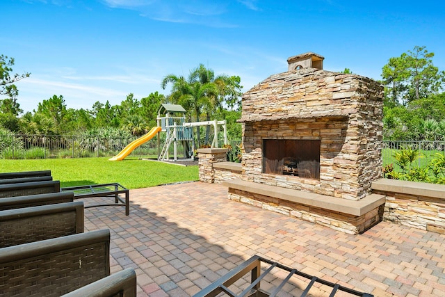 view of patio / terrace with an outdoor stone fireplace and a playground