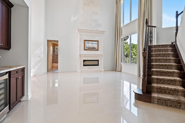 interior space featuring a high ceiling, beverage cooler, tile patterned flooring, and sink