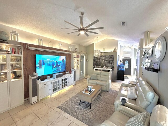 living room with lofted ceiling, light tile patterned floors, ceiling fan, and a textured ceiling