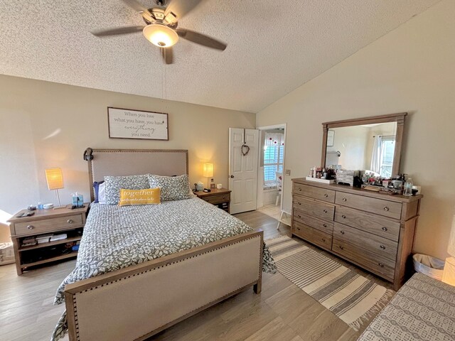 bedroom featuring ensuite bath, vaulted ceiling, a textured ceiling, and ceiling fan