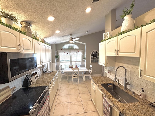 kitchen with sink, appliances with stainless steel finishes, backsplash, light stone countertops, and light tile patterned flooring