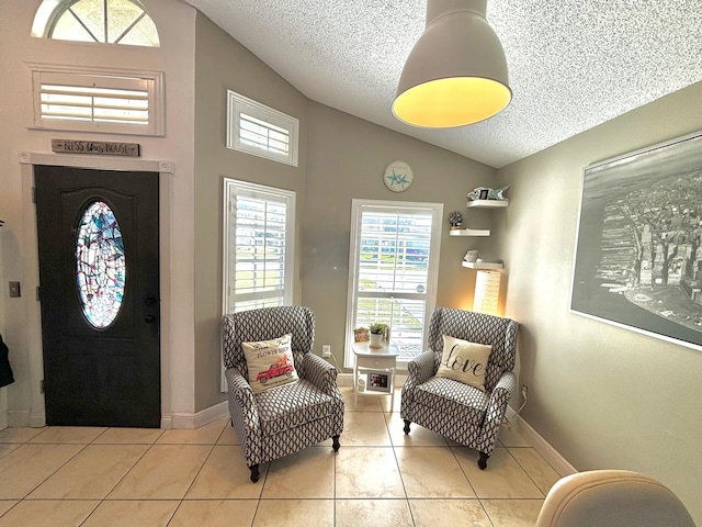 entryway with vaulted ceiling, light tile patterned flooring, and a textured ceiling