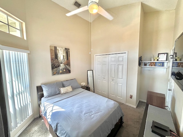 carpeted bedroom featuring a high ceiling, ceiling fan, and a closet