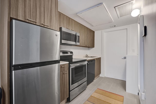 kitchen with stainless steel appliances, light tile patterned floors, and sink