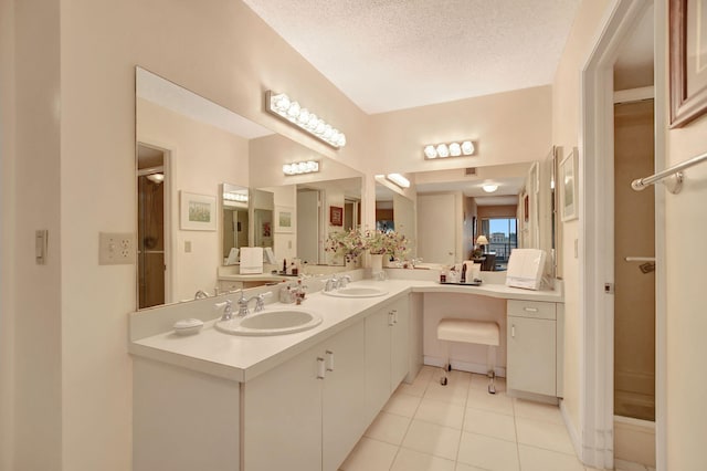 bathroom featuring tile patterned flooring, a sink, a textured ceiling, and double vanity