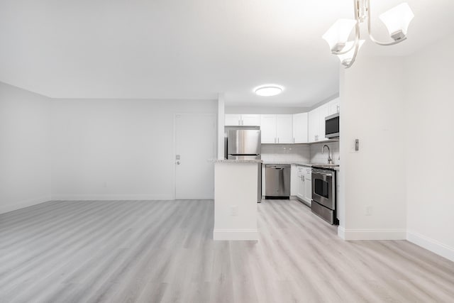 kitchen featuring stainless steel appliances, backsplash, pendant lighting, and white cabinetry