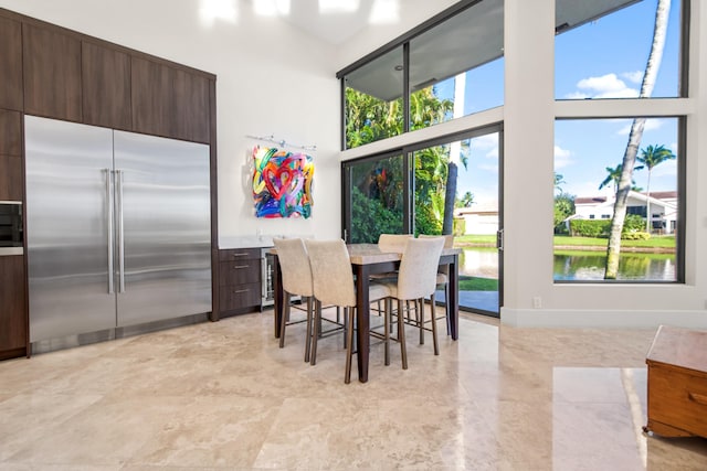 dining room featuring a high ceiling and a water view