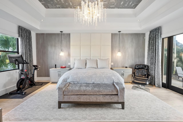 bedroom featuring multiple windows, a tray ceiling, and light wood-type flooring