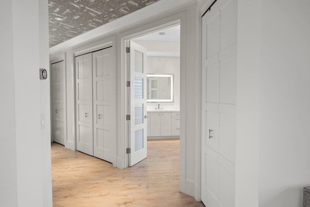 hallway with light hardwood / wood-style floors and sink