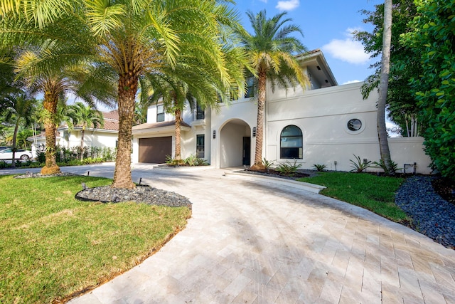 mediterranean / spanish house featuring a front yard and a garage