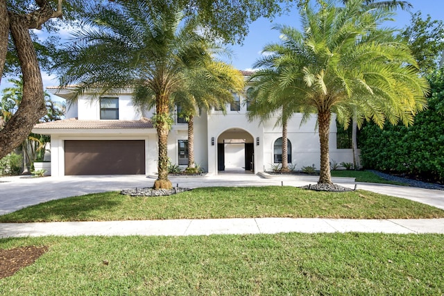 mediterranean / spanish home featuring a garage and a front lawn