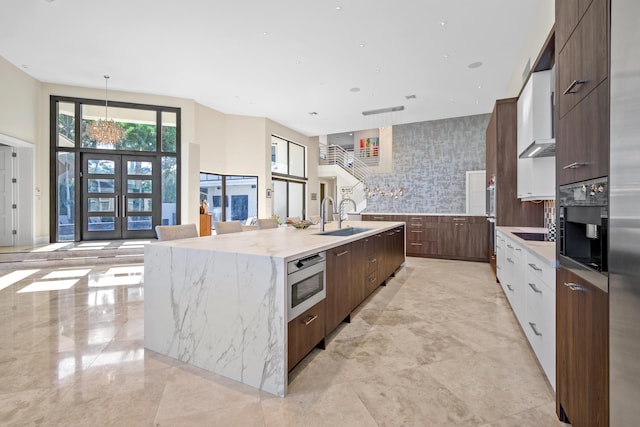 kitchen featuring oven, a large island, backsplash, white cabinets, and sink