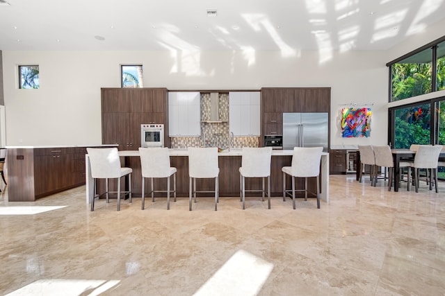 kitchen featuring a large island, appliances with stainless steel finishes, a kitchen breakfast bar, and white cabinetry