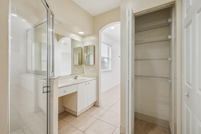 bathroom with tile patterned flooring, a shower with door, and vanity