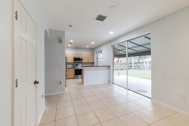 kitchen featuring kitchen peninsula, appliances with stainless steel finishes, light tile patterned flooring, and light brown cabinets