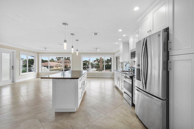 kitchen featuring decorative light fixtures, white cabinets, stainless steel appliances, and a kitchen island