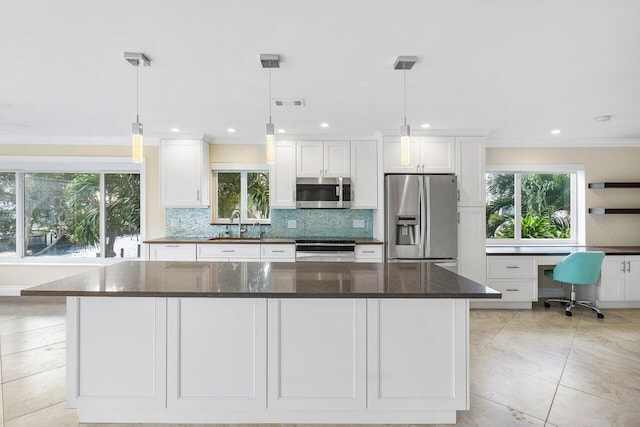 kitchen with appliances with stainless steel finishes, pendant lighting, dark stone countertops, and white cabinets