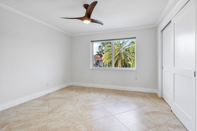 tiled empty room with ceiling fan and ornamental molding