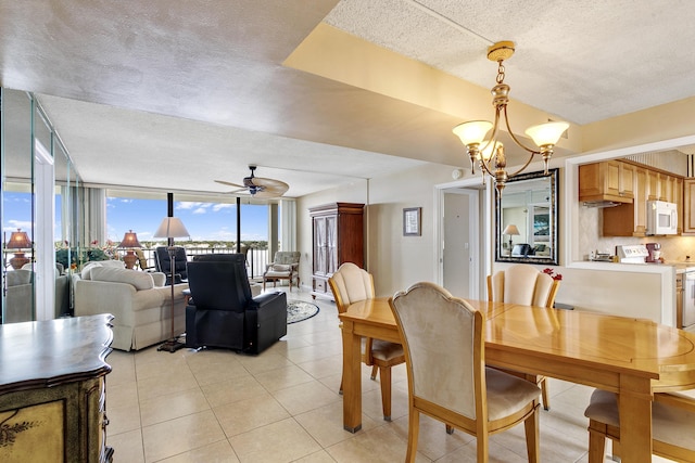 dining area featuring a textured ceiling, light tile patterned floors, ceiling fan with notable chandelier, and expansive windows