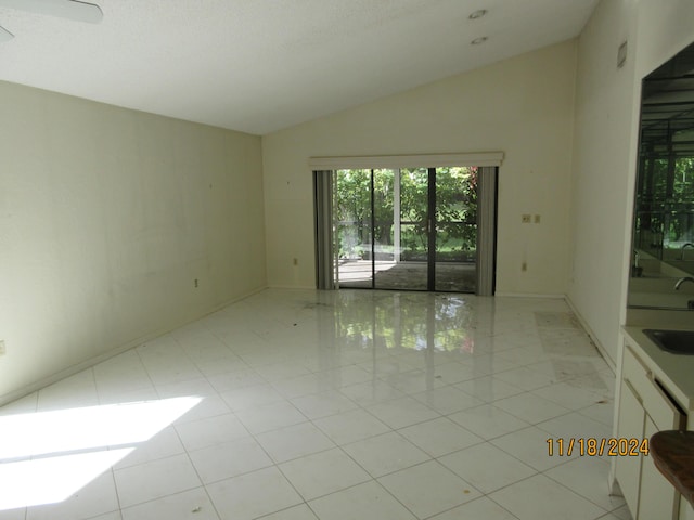 unfurnished room with sink, vaulted ceiling, and light tile patterned floors