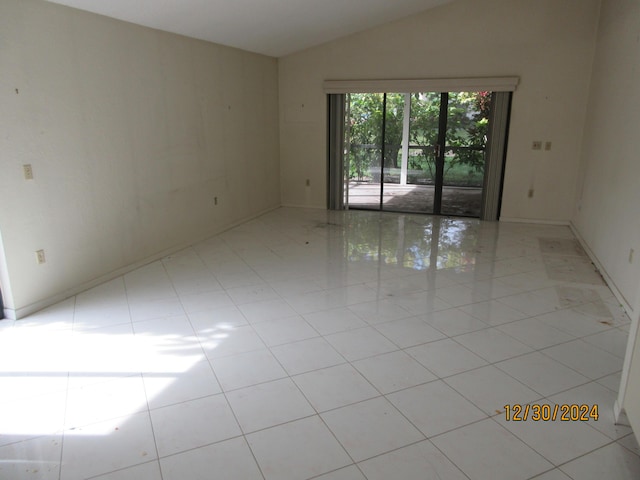 empty room with vaulted ceiling and light tile patterned flooring