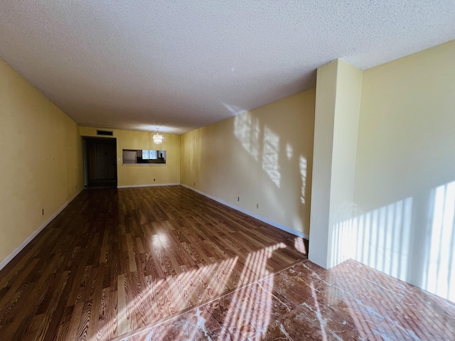 unfurnished living room with a textured ceiling, an inviting chandelier, and hardwood / wood-style floors