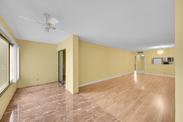 unfurnished living room featuring visible vents, a textured ceiling, and ceiling fan