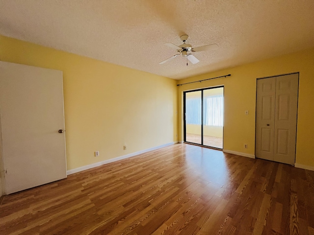 empty room with ceiling fan, a textured ceiling, and hardwood / wood-style flooring