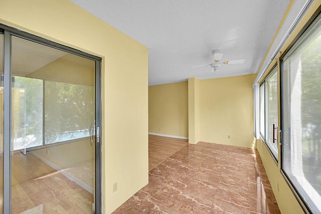 empty room with ceiling fan and a healthy amount of sunlight